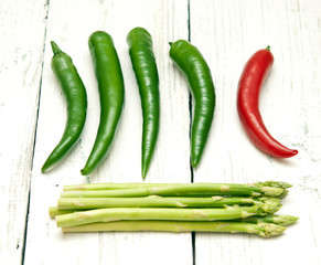 Green and red peppers and asparagus on a wooden background