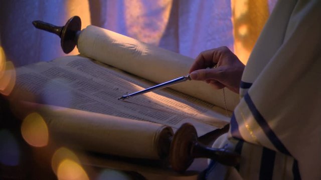 Close-up of opened Torah, reader's hand following lines with stylus