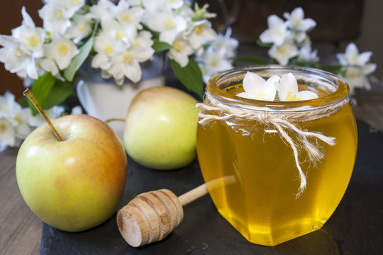 Apple and honey, traditional food of jewish New Year - Rosh Hashanah with blooming branch and flowers of jasmine on black stone board