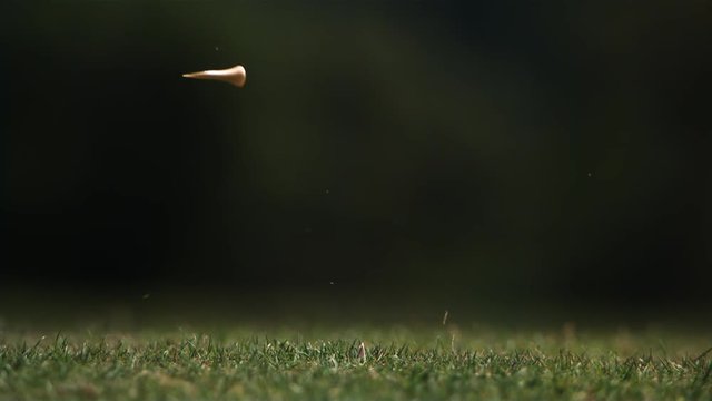 Close-up of golf ball on tee and club head striking it in ultra-slow motion