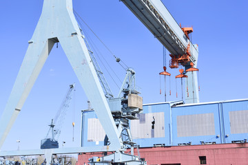 Obraz premium Wharf or shipyard of Hamburg Harbor, Germany. Harbor cranes and production halls at a commercial dock. Industry buildings.