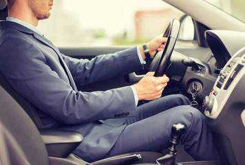 close up of young man in suit driving car