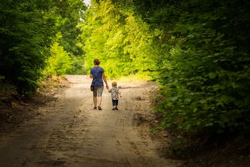 Mother and child walking by forest path