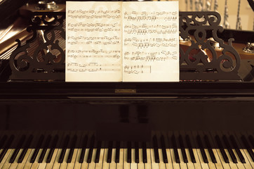 Musical notes on black piano, close up