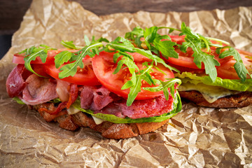 Fresh homemade BLT sandwich on grilled bread with bacon, lettuce, beef tomato, red onions, wild rocket and chips