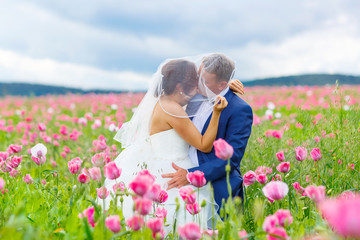 Happy wedding couple in pink poppy field