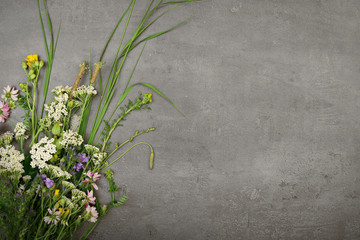 Fresh meadow flowers arranged on stone desk with space for text.