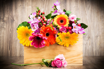 Fototapeta na wymiar Box of mixed flowers on wooden background