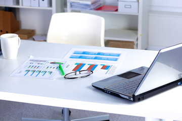 Office table with blank notepad and laptop