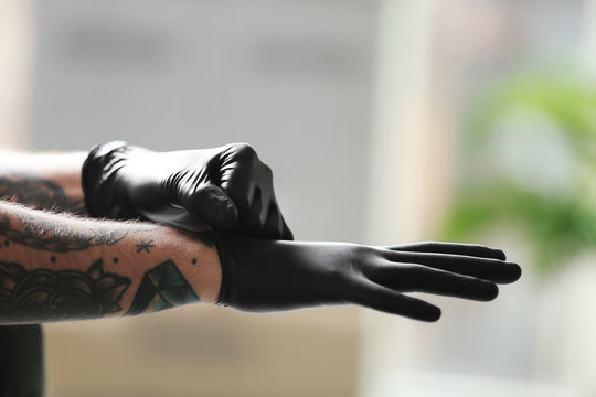Naklejki Man with tattoo wearing black latex gloves on blurred background