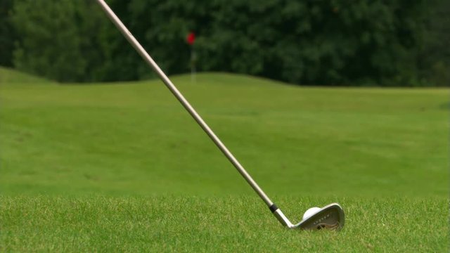 Wedge appears near golf ball in rough and is swung; ball disappears and club is flung