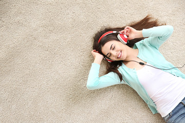 Beautiful girl with headphones lying on floor