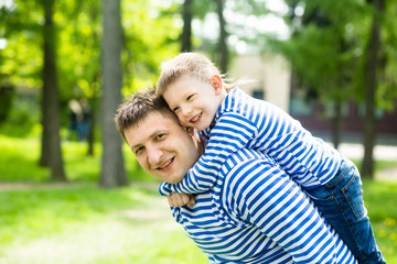 Father and son in the same striped shirts in the park on a sunny summer day