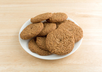 Oatmeal sugar free cookies on a white plate atop a wood table top.