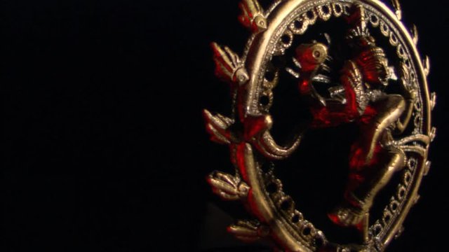 Encircled image of golden Shiva with red highlights rotating through dark frame