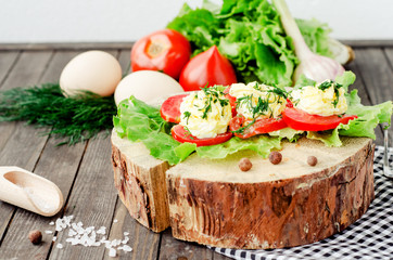 snacks , fresh tomatoes stuffed with eggs, melted cheese , mayonnaise and garlic with dill and lettuce on a wooden background