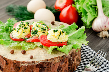 snacks , fresh tomatoes stuffed with eggs, melted cheese , mayonnaise and garlic with dill and lettuce on a wooden background