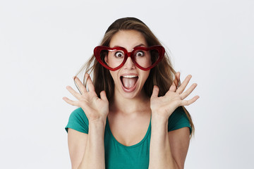 Surprised young woman in heart shaped spectacles