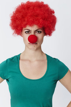 Annoyed clown in red wig, portrait