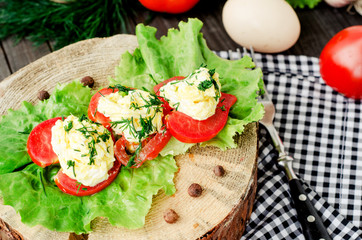 snacks , fresh tomatoes stuffed with eggs, melted cheese , mayonnaise and garlic with dill and lettuce on a wooden background