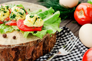 
snacks , fresh tomatoes stuffed with eggs, melted cheese , mayonnaise and garlic with dill and lettuce on a wooden background
