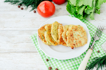 
vegetable breakfast or lunch , zucchini pancakes with dill , fresh tomatoes , lettuce and herbs on a wooden background