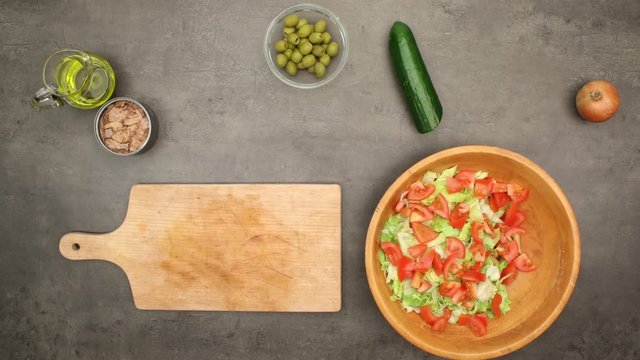 Tuna salad with pasta and vegetables. Top view with slowly zoom on recipe ingredients and preparation on grey kitchen table. 4K stopmotion animation.