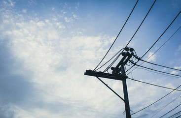 Electricity cable  on the pole with fluffy clouds and sky on  blue  tone background