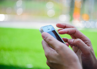 Young girl sitting on green grass with mobile phone.woman using