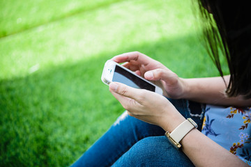 Young girl sitting on green grass with mobile phone.woman using