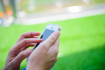 Young girl sitting on green grass with mobile phone.woman using