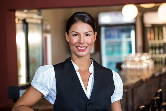Portrait of waitress standing at bar counter