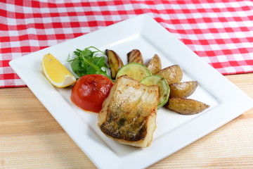 Fish grilled with vegetables on a wooden table