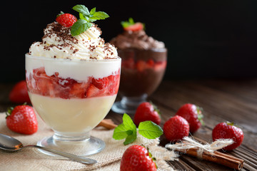 Vanilla pudding with strawberries, mascarpone and whipped cream on black background