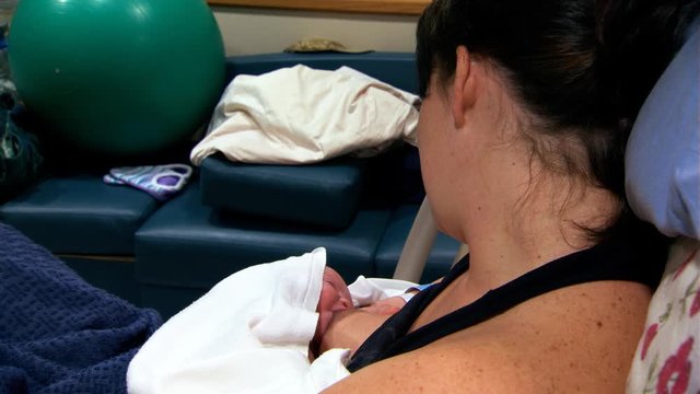 Face of young woman as she breast-feeds her newborn baby
