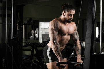 Obraz na płótnie Canvas Muscular bodybuilder guy doing exercises with dumbbells in gym