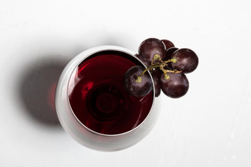 a glass of wine with bunch of grapes on white background top view
