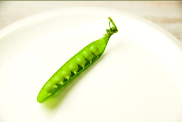 Green pea pod on the  big white plate.