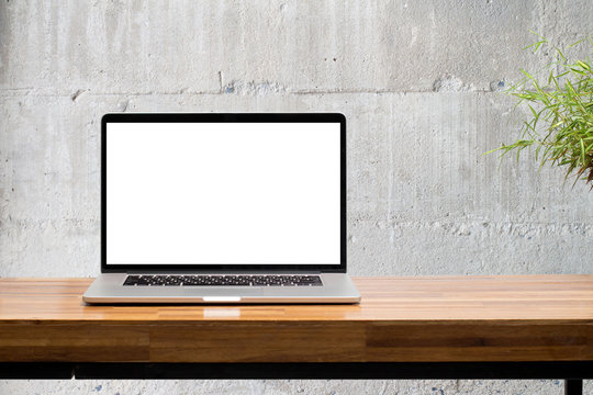 laptop on wooden desk with concrete wall background