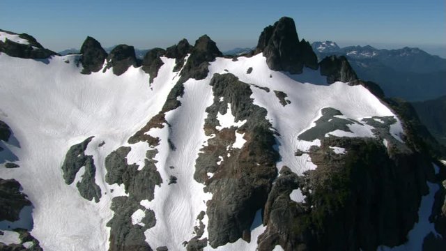 Low flight over snowfields of jagged peak in British Columbia, Canada