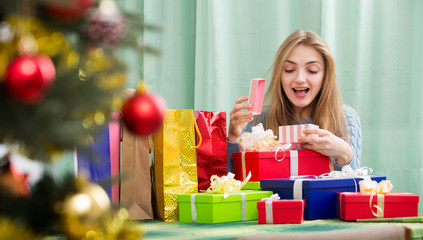 Obraz na płótnie Canvas Happy girl opening Christmas present and smiling