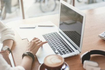 Young woman freelancer working with laptop in cafe
