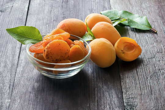 Ripe fresh apricots  with green leaves and dry on dark wooden table.