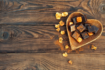 chocolate candies on heart plate on wooden table. View from above
