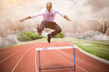Composite image of businessman jumping a hurdle