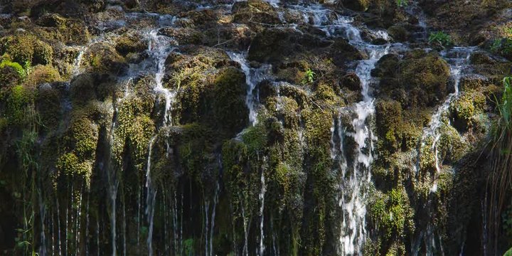 Streams of water trickling over ledge of mossy rocks