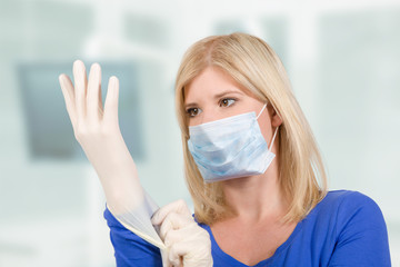 Krankenschwester zieht Latexhandschuhe an