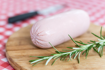 Salami sausage and rosemary on the kitchen wooden board.