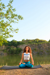 Young woman is practicing yoga near river