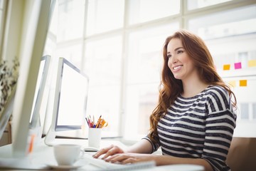 Smiling businesswoman working on computer in creative office